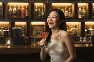 Asian woman drinking a cocktail at a bar at night. photo