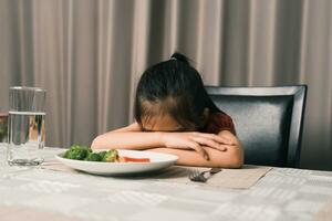 Little cute kid girl refusing to eat healthy vegetables. Children do not like to eat vegetables. photo