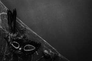 Halloween party concept with black party fancy mask on cobweb with black background. photo