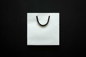 White shopping paper bag on black background for Black Friday shopping sale concept. photo