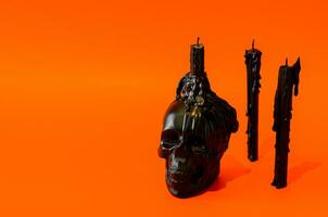 Black skull and candles put on orange background. Halloween party concept. photo