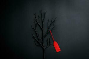 Black tree with branches with red price tag on black background for Black Friday shopping sale concept. photo