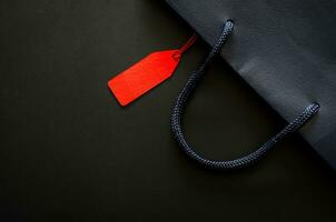 Dark blue shopping paper bag with blank red price tag for Black Friday shopping sale concept. photo