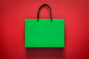Green shopping paper bag on red background for Black Friday shopping sale concept. photo