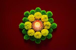 Clay diya lamp lits to celebrate for Diwali festival with colorful flowers on dark red background. photo