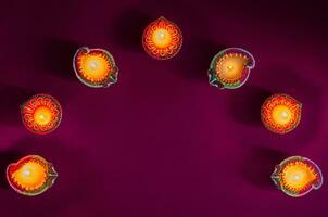 Colorful clay diya lamps lit to celebrate for Diwali festival on purple background. photo