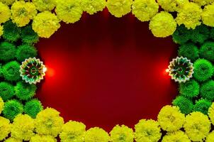 Clay diya lamps lit to celebrate for Diwali festival with colorful flowers on empty dark red background. photo