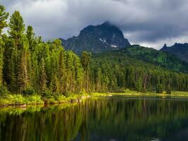 Lake Svetloye in Ergaki on an summer morning among the taiga rocks with blue sky in the warm sun and trees Mountain sunny landscape. photo