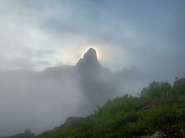 Mañana Dom detrás el montaña cima, el amanecer en el brumoso montañas. atmosférico fantasmal minimalismo con grande montaña tapas en nublado cielo. Oeste sayanos. foto