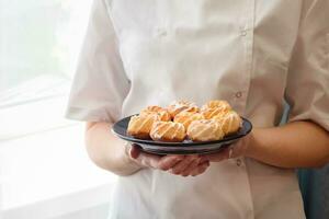 Cropped image of Woman chef holding fresh and tasty freshly baked coconut cookies. photo