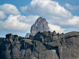 montaña pico en blanco nubes el pico sube entre el blanco nubes en el antecedentes un profundo azul cielo y el Dom creciente mediante el nubes foto