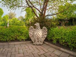 un águila hecho de piedra, un águila escultura en interior y paisaje diseño. interior verde patio. abakán. foto