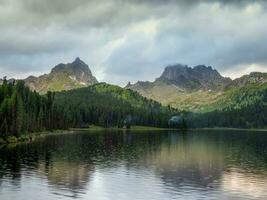 Amazing huge cloud above giant mountains. Raindrops on mountain lake. Wonderful droplets on lake water. Low clouds. Cloudy sky. Wonderful atmospheric ghostly highland landscape. West Sayans. photo