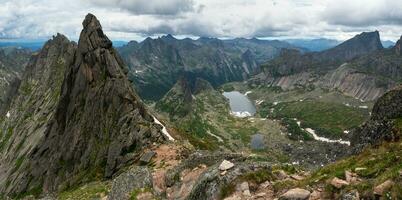 Pointed cliffs mountainside. Ghost rocks. Awesome scenic mountain landscape with big cracked pointed stones in misty rainy morning. Sharp rocks background. Western Sayans, Ergaki. Panoramic view. photo