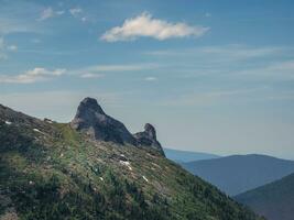 minimalista alpino paisaje con diagonal genial montaña cresta verde bosque y rocas debajo azul cielo. escénico soleado montaña paisaje con alto montaña rango en luz de sol. foto