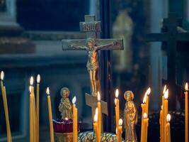 Church candles burn in front of a statuette of the crucifixion of Jesus in the Orthodox Church. Christian faith and traditions. The theme of faith and God, religion and traditions. photo