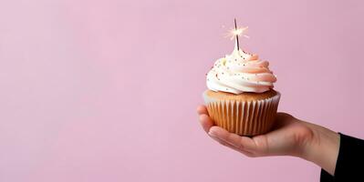 Small birthday cake with a sparkle held by hand photo