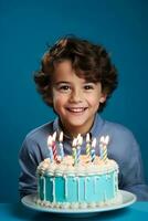 Little boy and birthday cake with candles on green background photo