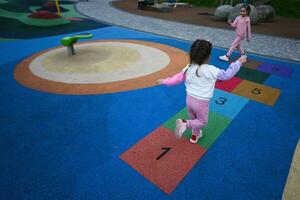 Little girl playing hopscotch at playground in the park. photo