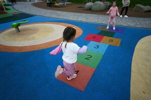 Cute little girl playing hopscotch game in the playground. photo