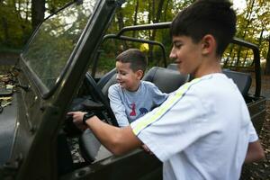 dos Niños conducción un safari vehículo en un otoño bosque. foto