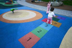 Little girl playing hopscotch game in park. Early education concept photo
