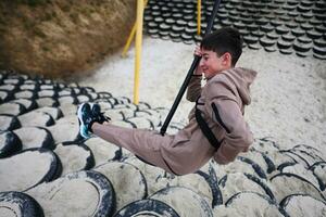 Young boy in sportswear doing roolling push-ups on a playground. photo