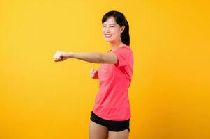 Portrait beautiful young asian sports fitness woman happy smile wearing pink sportswear posing exercise training workout isolated on yellow studio background. wellbeing and healthy lifestyle concept. photo