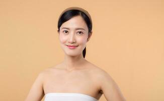 beauty asian young woman model with fresh glowing hydrated facial skin. girl person with natural makeup and healthy skin portrait isolated on beige studio background. spa treatment, skin care concept. photo
