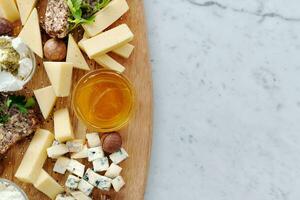 Top view of cheese platter with various types of cheese on white marble background photo