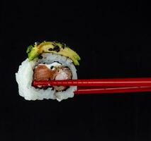 sushi on a black background with chopsticks, close-up photo