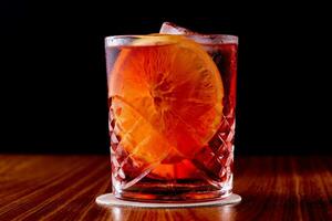 Cocktail with orange and ice in a glass on a black background photo