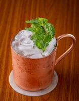 Mint Cocktail in copper mug with ice on a wooden table photo