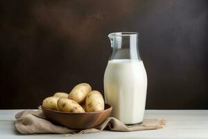 Jug and glass of potato milk, bowl of raw potatoes, copy space. Alternative plant based milk. Superfood. AI generated. photo