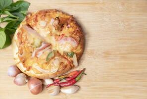 Pizza on wooden board with fresh peppers and basil with garlic on copy space background photo