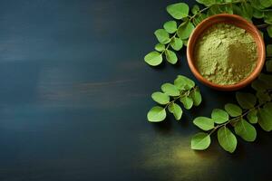Fresh moringa leaves and powder on dark blue background with copy space. AI generated. photo