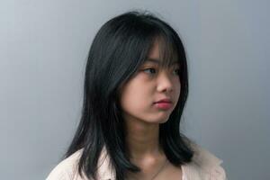 Young beautiful Asian teenage girl showing a sad, disappointed expression on background. photo