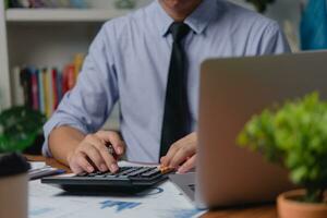 Businessman working on laptop and accounting financial marketing report document investment paperwork. hands of accountant using calculator to calculate tax refund economy. photo