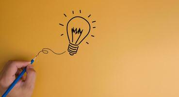 Hand pencil draw light bulb creativity innovation solution concept on yellow background.copy space photo