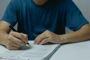 Hand holding pen checklist paper work on desk. Signing information contract and agreement. Checkbox report questions customer services. Write education and learning homework. photo