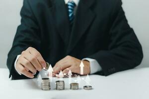 Businessman holding coins stacking with up arrow for financial banking interest rate from money saving and business investment growth from dividend concept. photo