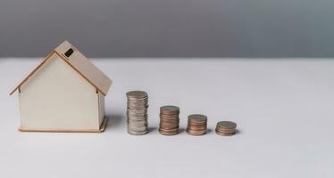 Stacked of Coins and House Model. Business investment and saving money finance, tax Interest rates for loans and real estate prices concept. photo