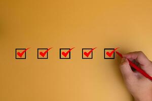 Hand using pen Checklist concept, Check mark on yellow background with copy space photo