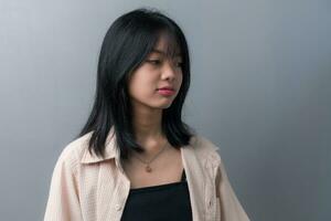 Young beautiful Asian teenage girl showing a sad, disappointed expression on background. photo