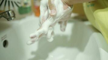 ein Frau ist Waschen ihr Hände mit ein sinken mit Schaum im das Badezimmer. video