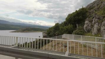 a view of a bridge over a lake with mountains in the background video