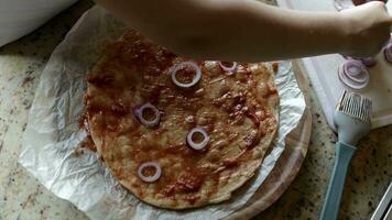 a person is putting onions on a pizza video