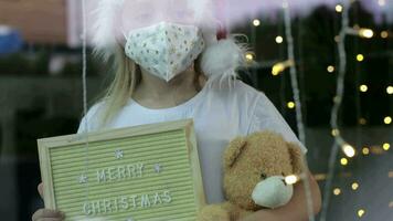 uma menina dentro uma branco mascarar segurando uma borda e uma Urso de pelúcia Urso video