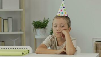 a boy wearing a party hat sits at a table video