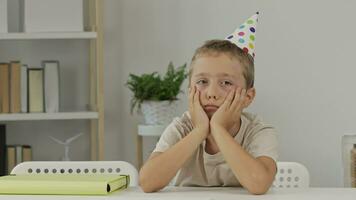 a boy wearing a party hat sits at a table video